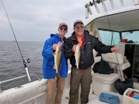 two men standing on a boat holding up fish