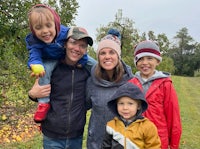 a family posing for a photo in an apple orchard